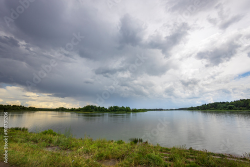 A cloudy sky over a lake with a few trees in the background