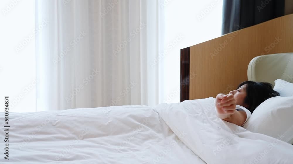 Rear view of asian woman wake up in the morning, sitting on white bed and stretching Rear view of asian woman wake up in the morning, sitting on white bed and stretching