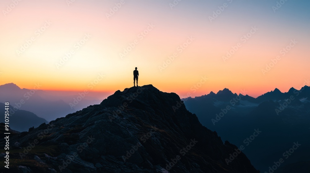 A dramatic silhouette of a person standing on a mountain peak at sunset A dramatic silhouette of a person standing on a mountain peak at sunset