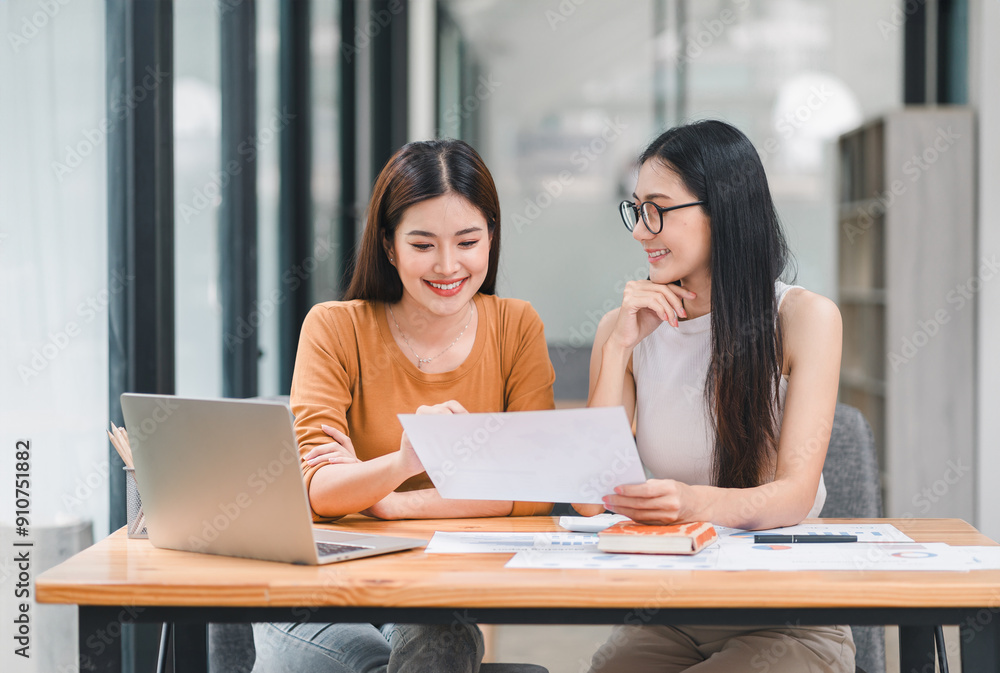 Two young Asian businesswomen discuss a new startup project idea, analyzing planning and financial statistics, investment market, at the office. Two young Asian businesswomen discuss a new startup project idea, analyzing planning and financial statistics, investment market, at the office.