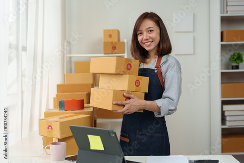 Small startup business, SME owner, female entrepreneur working, standing holding a parcel box. Checking orders online To prepare to pack boxes for sale Delivered to customers online business ideas.