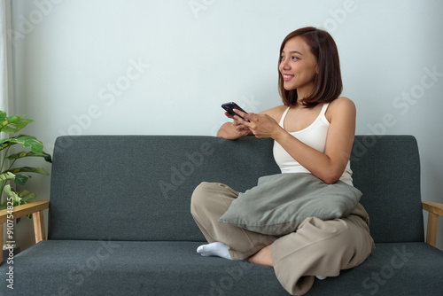 Confident Asian woman sitting on sofa While working on a laptop computer in the living room at home Working from home, New Normal and learning in the online world holiday working concept.