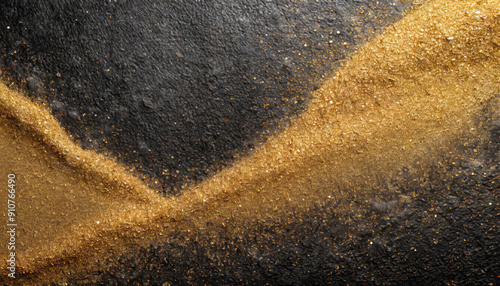 Glittering gold dust and shiny golden sand stripes poured on black rough rock wall or surface with small granulated dark stones luxurious abstract grainy texture, wallpaper or background.
