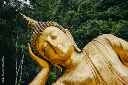 Close up of Reclining Buddha gold statue face with mountain background inThailand.