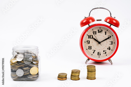 A coins bank, coins and red clock isolated with white background.