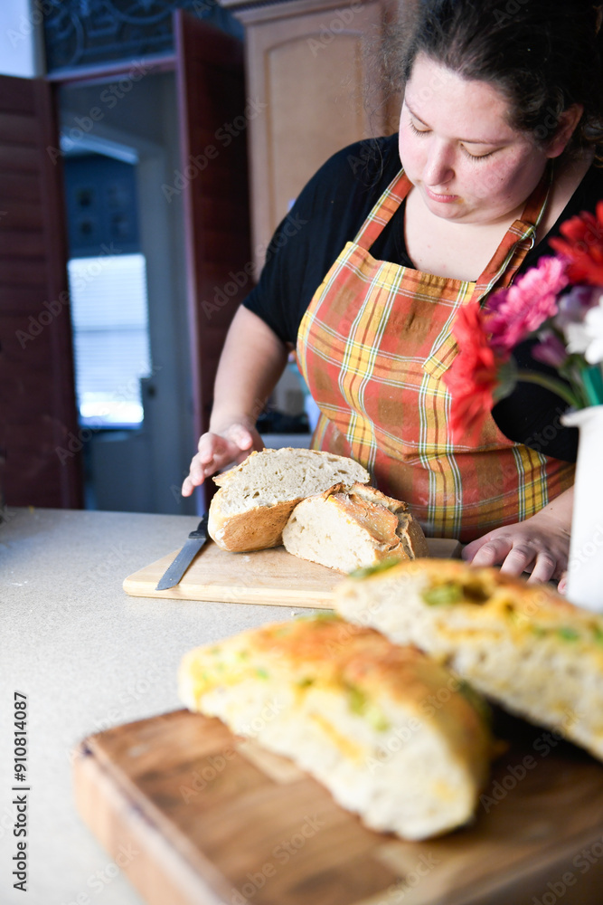 Woman in plaid apron slicing sourdough bread. Woman in plaid apron slicing sourdough bread.