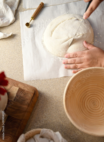 Hands cutting dough with a knife on parchment paper, next to a p photo