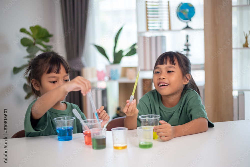 Two young girls are sitting at a table, playing with a science experiment Two young girls are sitting at a table, playing with a science experiment