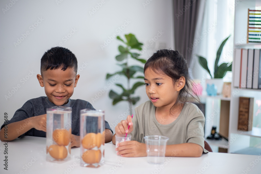 Two children are playing with a science experiment involving water and eggs Two children are playing with a science experiment involving water and eggs