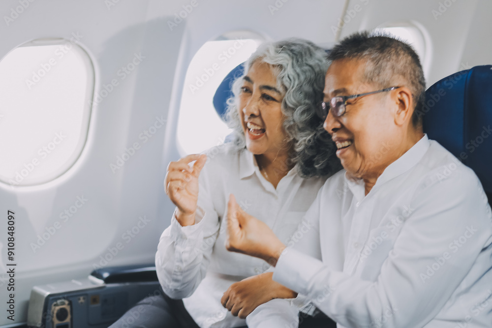 Fototapeta premium .A mature couple enjoys a plane ride sitting near the window. They looked out into the sky. Immerse yourself in the scenery and excitement of the journey. To create precious memories together