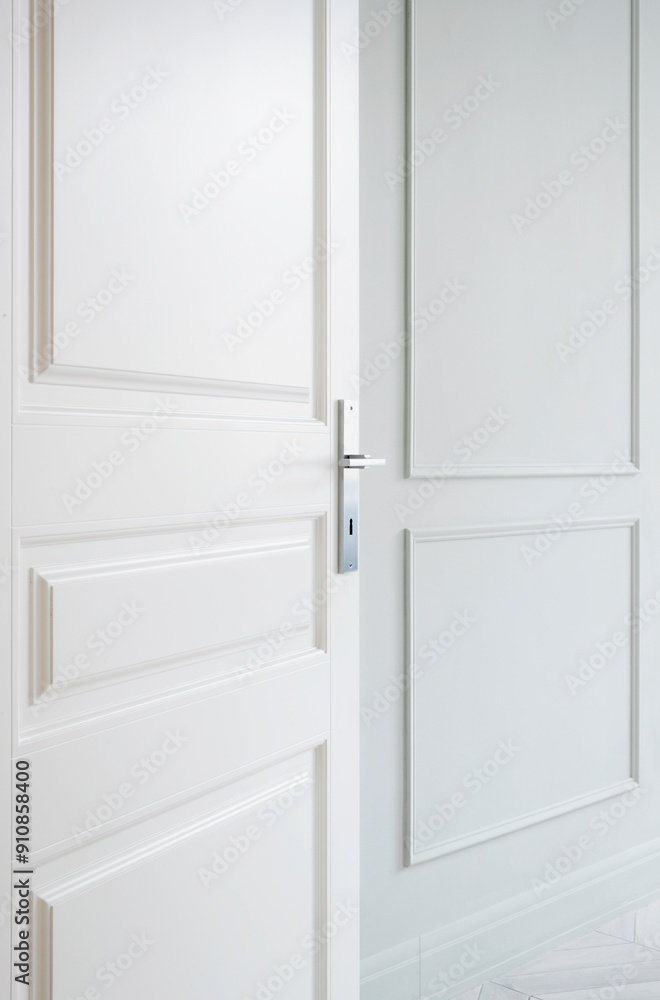 A modern white door stands partially open in a minimalist space featuring soft white walls and elegant paneling. Modern white door partially open in minimalist interior design A modern white door stands partially open in a minimalist space featuring soft white walls and elegant paneling. Modern white door partially open in minimalist interior design