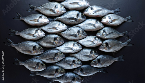 Freshly caught dorades lie next to each other in a symmetrical pattern as a background.