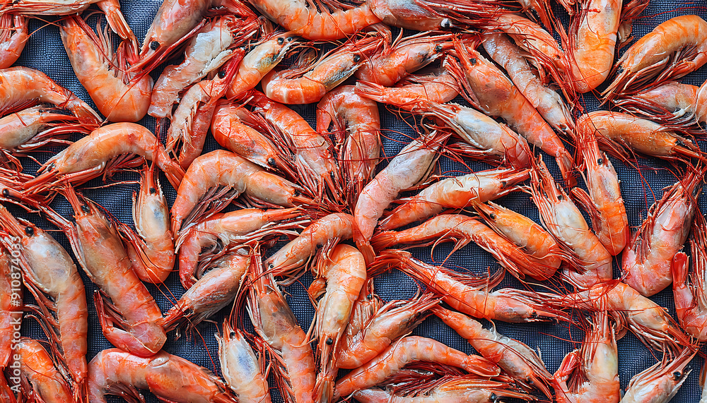 Freshly caught gambas lie next to each other in a symmetrical pattern as a background. Freshly caught gambas lie next to each other in a symmetrical pattern as a background.
