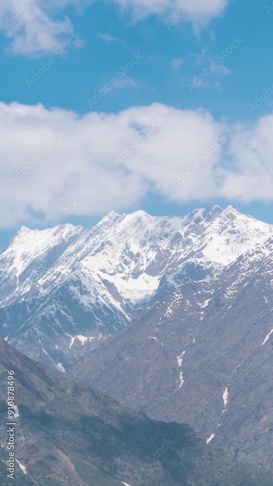 Vertical Time lapse of dancing clouds above the snow mountains. Winter mountain landscape. View from Keylong, Lahaul, India. Bright sunny day, cold atmosphere. Travel, trekking and holidays concept. Vertical Time lapse of dancing clouds above the snow mountains. Winter mountain landscape. View from Keylong, Lahaul, India. Bright sunny day, cold atmosphere. Travel, trekking and holidays concept.