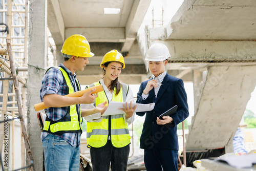 Contractor and architect looking at plan, tablet, laptop and talking about working on big project.