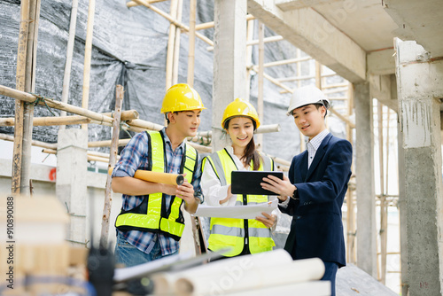 Contractor and architect looking at plan, tablet, laptop and talking about working on big project.