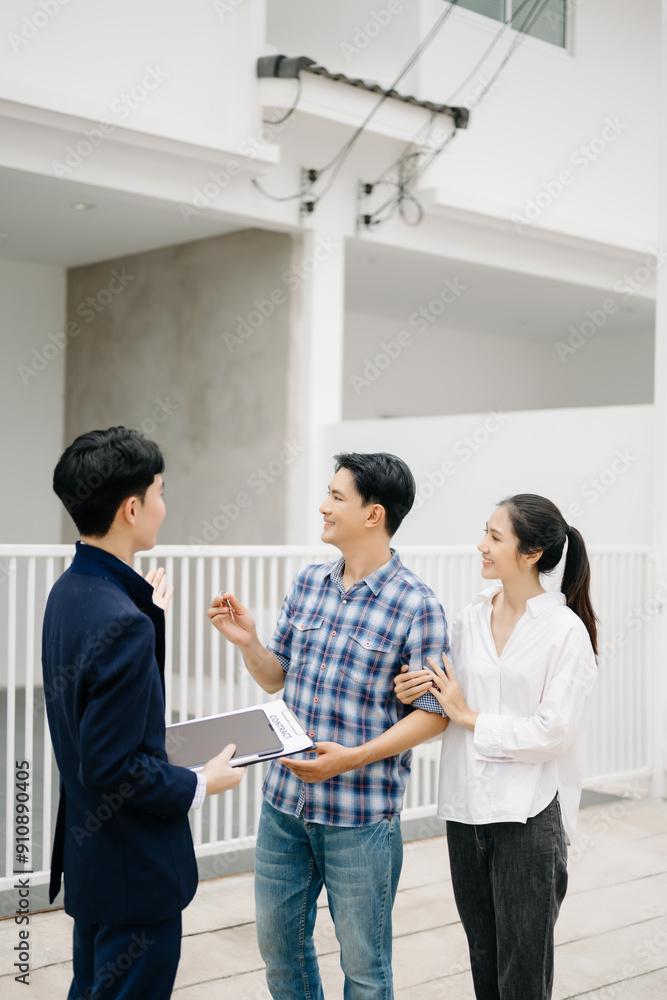 Asian man Real estate broker agent showing a house detail in her file to the young Asian couple lover looking and interest to buy it. Asian man Real estate broker agent showing a house detail in her file to the young Asian couple lover looking and interest to buy it.