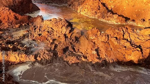 Muddy water flowing over earth in a construction project, showcasing the need for erosion control - in slow motion photo