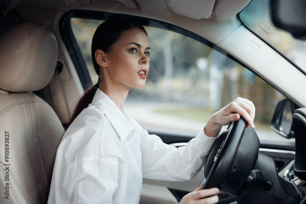 Woman driving car, hand on steering wheel, surprised expression at camera, wearing white shirt Woman driving car, hand on steering wheel, surprised expression at camera, wearing white shirt