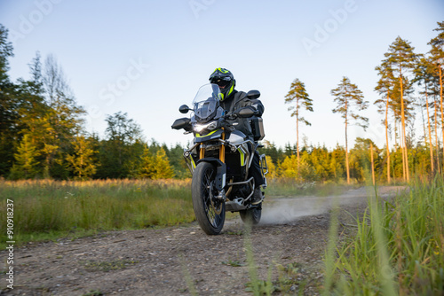 Driver riding motorcycle on empty road during sunset