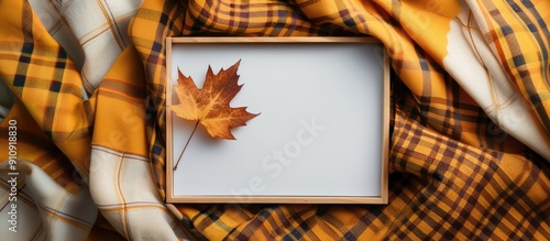 Top view of an empty white board surrounded by autumn themed elements like a maple leaf on a checkered yellow scarf perfect for a copy space image photo