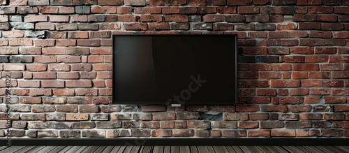 Copy space image of a sleek flat screen TV against a brick and wooden wall photo