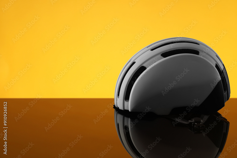 Fototapeta premium White protective helmet on mirror surface against orange background. Space for text