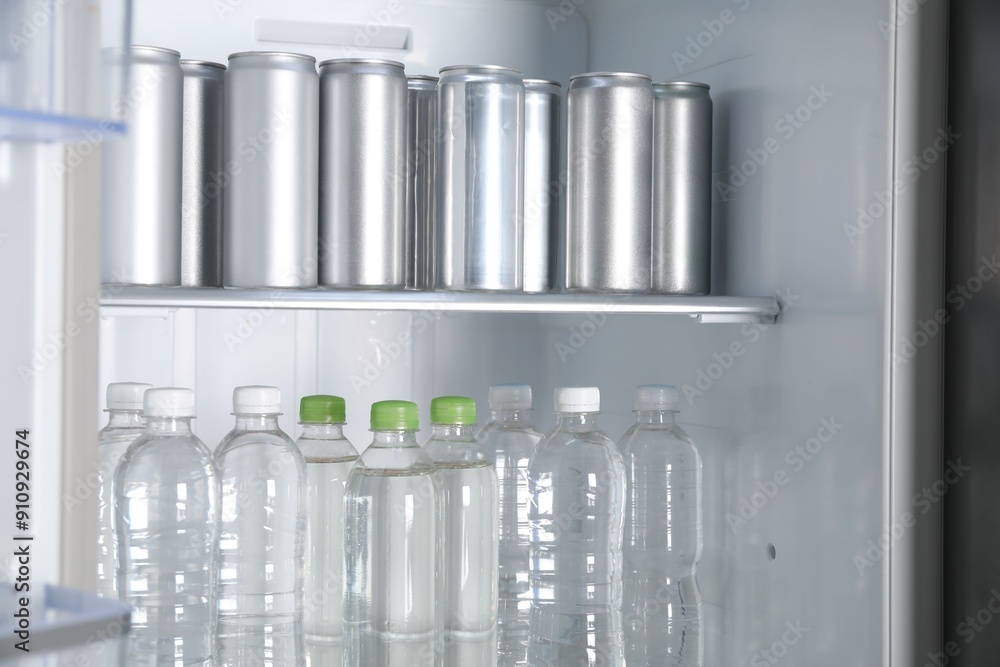 Cans of beer and water bottles in refrigerator, closeup Cans of beer and water bottles in refrigerator, closeup