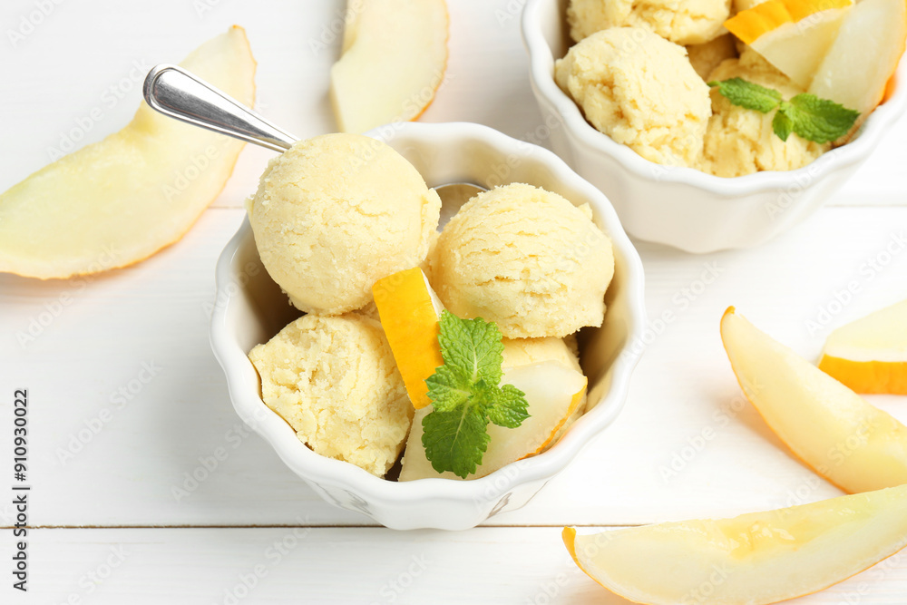 Scoops of melon sorbet with mint and fresh fruit in bowls on white wooden table, above view