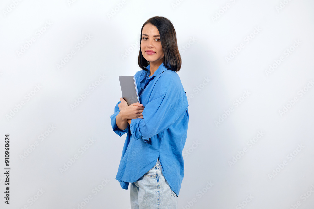 European brunette woman dressed in a blue blouse holds a laptop and goes to a meeting European brunette woman dressed in a blue blouse holds a laptop and goes to a meeting