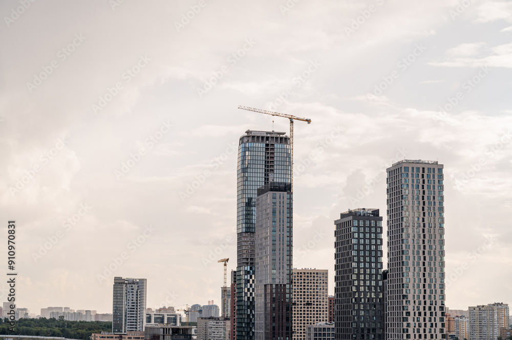 Construction site of a block of flats of the monolithic residential apartment building against blue sky. Tower cranes. Construction site of a block of flats of the monolithic residential apartment building against blue sky. Tower cranes.