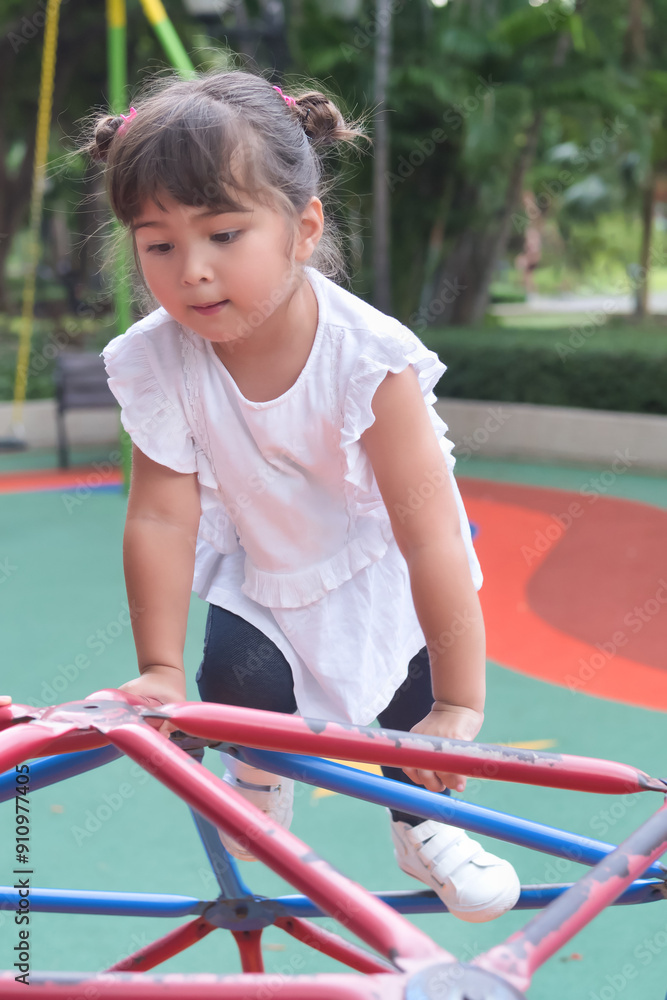 Happy smiling cute little girl, preschooler female kid playing in kid playground, climbing jungle gym or monkey bars Happy smiling cute little girl, preschooler female kid playing in kid playground, climbing jungle gym or monkey bars