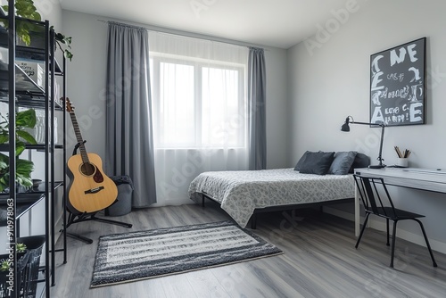 Bright bedroom with white walls, light grey wooden flooring, minimal furniture including an electric guitar, desk with black metal shelves, and single bed in neutral tones.