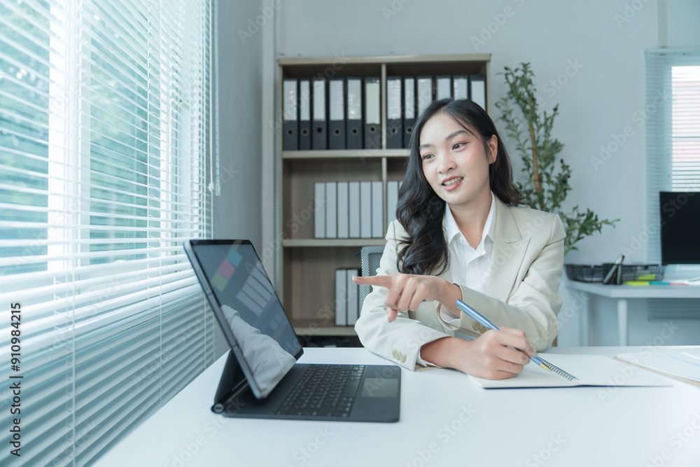 Asian businesswoman sitting in office, smiling happily at her work, using laptop computer, calculator. Asian businesswoman sitting in office, smiling happily at her work, using laptop computer, calculator.