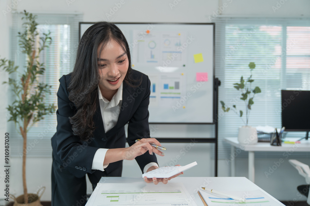 Asian businesswoman sitting in office, smiling happily at her work, using laptop computer, calculator. Asian businesswoman sitting in office, smiling happily at her work, using laptop computer, calculator.
