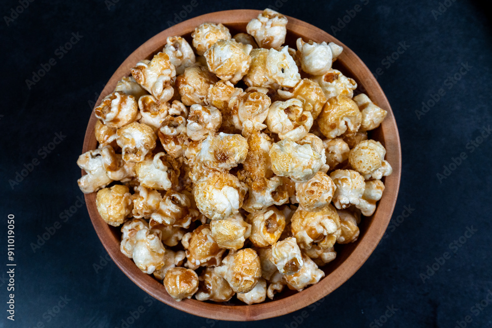 top view of pile of popcorn in wooden bowl on dark table top view of pile of popcorn in wooden bowl on dark table