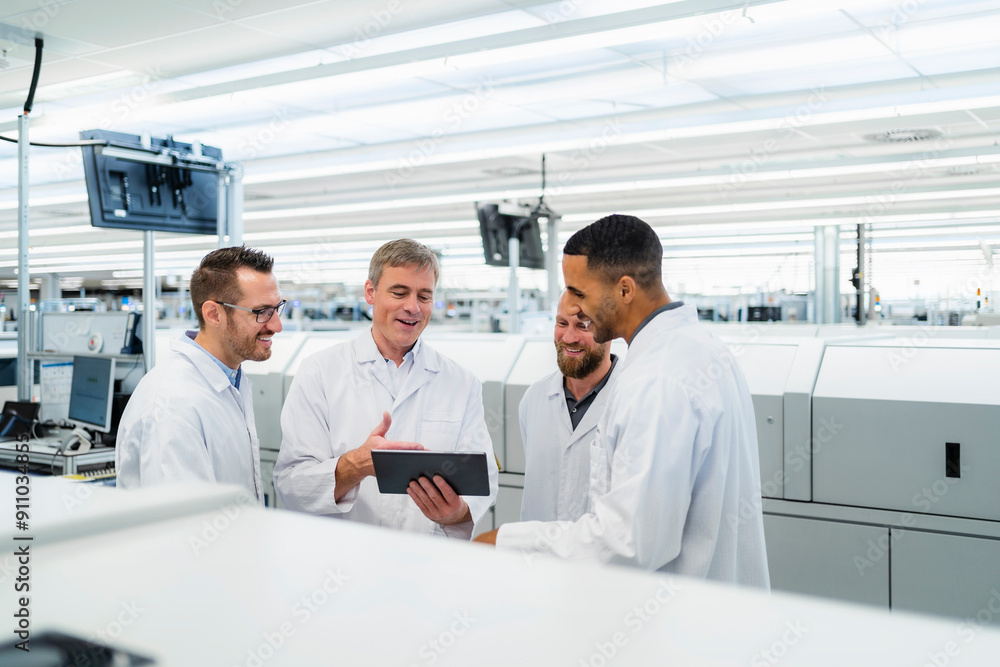 Team of competent electrical technicians in lab coats having meeting in electronics factory Team of competent electrical technicians in lab coats having meeting in electronics factory