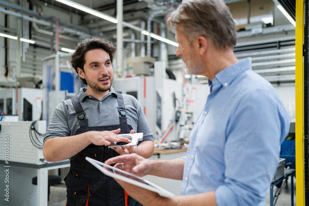Colleague explaining machine part to businessman at factory Colleague explaining machine part to businessman at factory