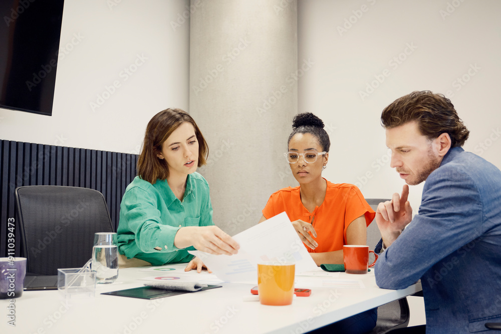 Focused multiracial business colleagues going through documents sitting in meeting room Focused multiracial business colleagues going through documents sitting in meeting room