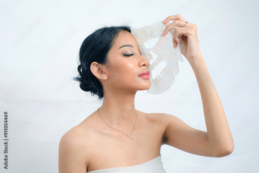 Radiant Asian Woman with Flawless Skin Using Face Mask on White Background Radiant Asian Woman with Flawless Skin Using Face Mask on White Background