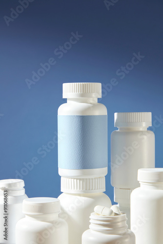 Medicine backdrop used for advertising pharmaceutical product, against on blue color background. A white medicine bottle with blank blue label, which placed above of plenty medicine bottles