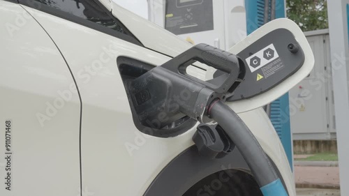 Close-up of plugging and unplugging an electric car charger at a charging station. Shows interaction with the charging port, unplugging process, and closing the car's charging flap photo