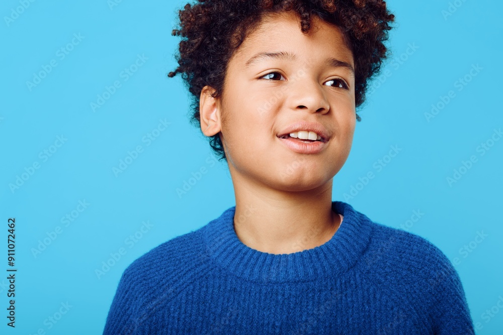 Bright and joyful portrait of an african american boy with curly hair against a vibrant blue background Bright and joyful portrait of an african american boy with curly hair against a vibrant blue background