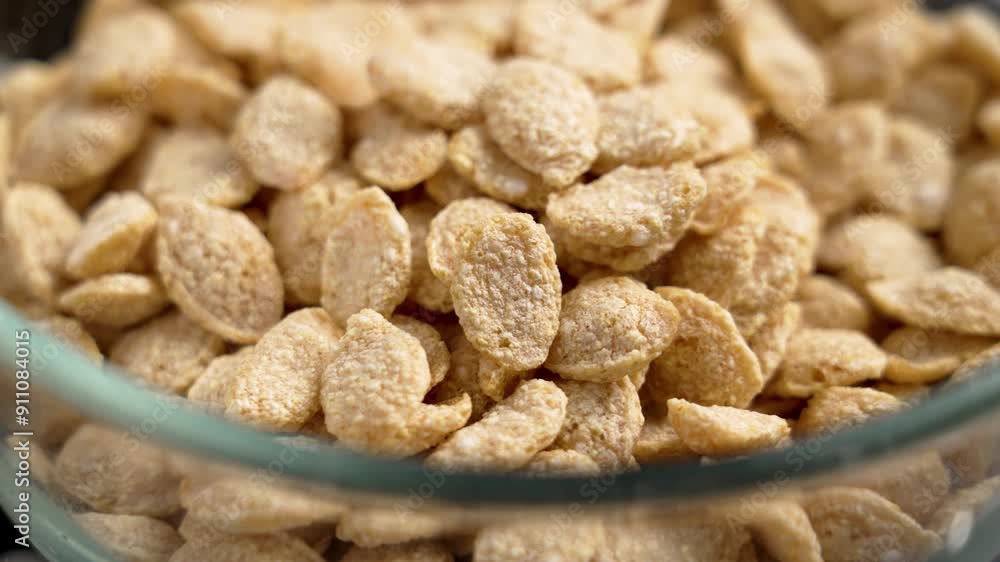Crispy breakfast cereal flakes in the form of grains in a glass transparent kitchen bowl close up. Organic nutritional food. Rotation Crispy breakfast cereal flakes in the form of grains in a glass transparent kitchen bowl close up. Organic nutritional food. Rotation