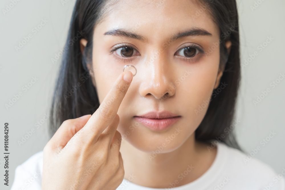Ophthalmology care, eye sight or vision. Closeup asian young woman, female hand holding and putting, wearing soft contact lens on face with finger, look into eye on background. Medicine and health. Ophthalmology care, eye sight or vision. Closeup asian young woman, female hand holding and putting, wearing soft contact lens on face with finger, look into eye on background. Medicine and health.