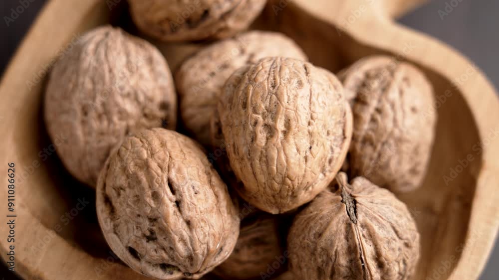 Ripe unshelled walnuts in shell in a shaped wooden craft bowl. Unpeeled raw nuts. Top view. Rotation Ripe unshelled walnuts in shell in a shaped wooden craft bowl. Unpeeled raw nuts. Top view. Rotation