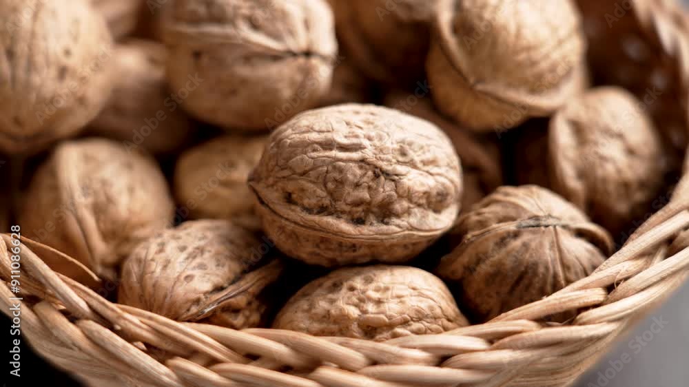 Fresh walnuts seeds in authentic wooden braided rattan bowl close up. Organic whole uncracked nuts in shells. Rotation Fresh walnuts seeds in authentic wooden braided rattan bowl close up. Organic whole uncracked nuts in shells. Rotation