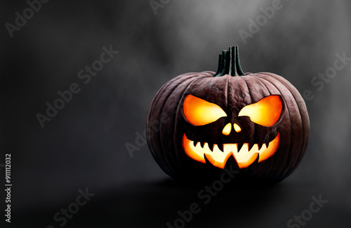 Obraz na płótnie A halloween pumpkin at night with a spooky, scary evil glowing face against a misty dark background. w salonie