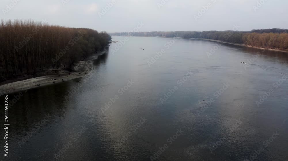 Drone descends towards surface of Danube river with woods on both riversides Drone descends towards surface of Danube river with woods on both riversides