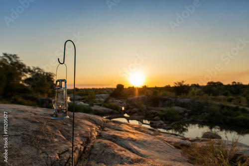 A lantern placed next to a river during sunset.